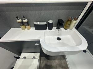 a white sink in a bathroom next to a toilet at Burnbrae Apartment in Portree +8 photos