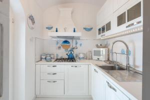 una cocina blanca con armarios blancos y fregadero en Villa Navarra, en Praiano