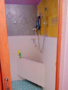 een badkamer met een douche en een witte tegelmuur bij Gooday homestay in Skudai