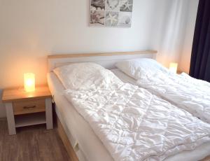 uma cama branca com duas velas numa mesa em Ferienwohnung Steffens - "Wicheldorfstraße" em Grömitz