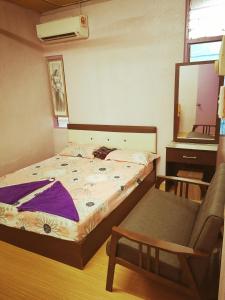 een slaapkamer met een bed, een stoel en een spiegel bij Gooday homestay in Skudai