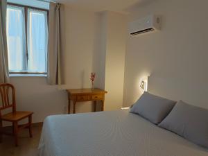 1 dormitorio con 1 cama, 1 silla y 1 ventana en Estudios Playa De Cóbreces, en Cóbreces