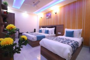 um quarto de hotel com duas camas e flores nele em Hotel Grand TuCasa Near International Airport em Nova Deli
