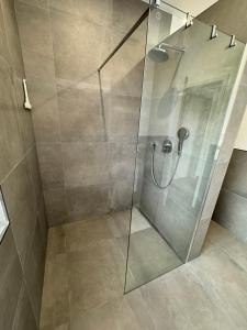 W łazience znajduje się prysznic ze szklanymi drzwiami. w obiekcie Schönes Ferienhaus mit Sauna am Harkebrügger See in der Nähe von Oldenburg w mieście Barßel