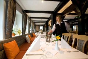 een vrouw aan een lange tafel in een restaurant bij Ferien- und Reitsport Hotel Brunnenhof in Suhlendorf