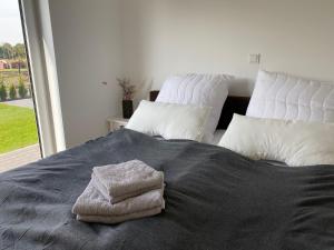 a bed with two white pillows and towels on it at Schönes Ferienhaus mit Sauna am Harkebrügger See in der Nähe von Oldenburg in Barßel