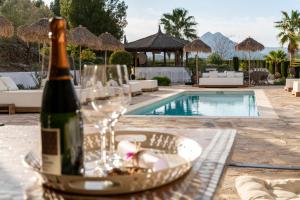 uma garrafa de vinho sentada numa mesa ao lado de uma piscina em Cuatre Finques em Jalón