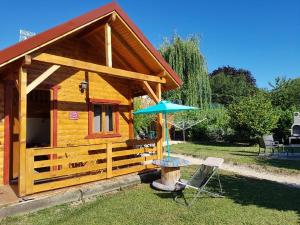 eine kleine Holzhütte mit einem Tisch und einem Sonnenschirm in der Unterkunft Le petit chalet jurassien in Jouhe