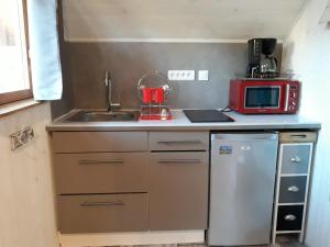una cucina con lavandino e forno a microonde rosso di Le petit chalet jurassien a Jouhe Altre 7 foto