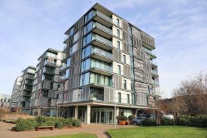a tall glass building with a park in front of it at 2 Bedroom 2 Bathroom Apartment in Kings Cross Station in London