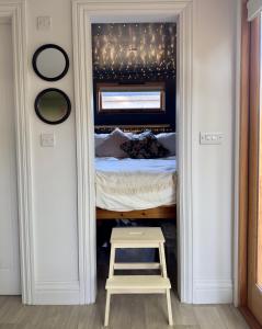 a bedroom with a bed and a stool in the doorway at The Snug: Dorset hideaway in Blandford Forum