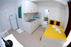 Cette chambre comprend une petite cuisine avec un lit jaune. dans l'établissement Vila Renato Ksamil, à Ksamil