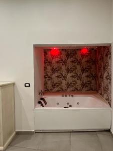 een bad met twee rode lampjes aan de muur bij La Casa Di Eva in Siracusa