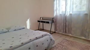 a bedroom with a bed and a table next to a window at Apartman Porfido in Mostar