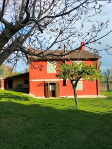 un bâtiment rouge avec un arbre devant lui dans l'établissement Stella del Mattino, à Gradara