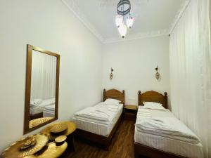 two beds in a room with a mirror and a table at Best Hotel Muqaddam in Bukhara