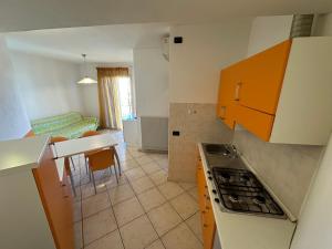 a kitchen with orange cabinets and a kitchen with a table at Residence Diana Frontemare - Agenzia Cocal in Caorle