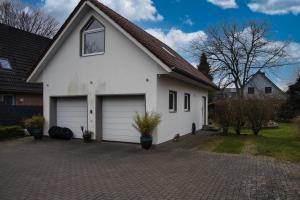 a white house with two garage doors on a driveway at HejU- Haus im Grünen in Rosengarten