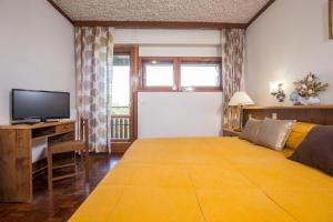 a bedroom with a large yellow bed and a television at Hotel Tre Cime Terminillo in Terminillo