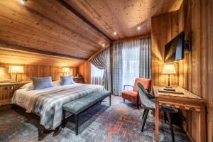 a bedroom with a bed and a desk and a chair at Hotel Le Samoyede in Morzine