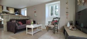 ein Wohnzimmer mit einem Sofa und einem Tisch in der Unterkunft Gîte La Grange de Germaine 