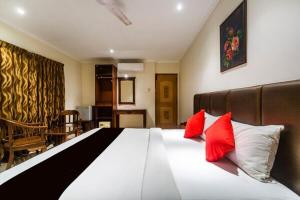 a bedroom with a large bed with two red pillows at Blossoms Hotel & Service Apartments in Chennai