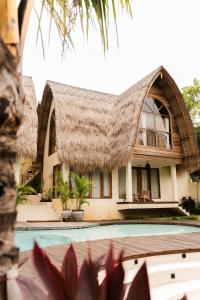 a house with a thatched roof and a swimming pool at Lulu's Villas in Uluwatu