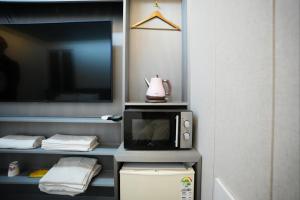 ein Zimmer mit Mikrowelle und Fernseher in der Unterkunft Shinchon Y Hotel in Seoul