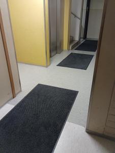 un couloir avec des tapis noirs à l'étage d'un bureau dans l'établissement Private Room next to Helsinki-Vantaa Airport, à Vantaa