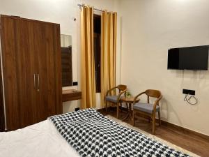 a bedroom with two chairs and a bed and a tv at Fourseasonkasauli in Solan