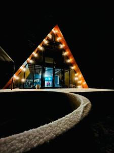 a pyramid building with lights on it at night at Cabana NucA-Frame in Satu Nou de Jos