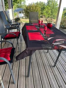 une table avec un tissu de table rouge sur une terrasse dans l'établissement Un petit îlot de confort - made in Finland, à Monflanquin