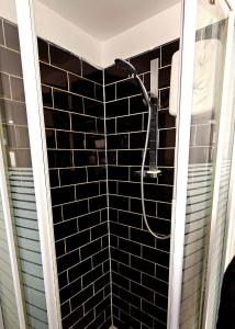 baño con ducha de azulejos negros en Wolves Living en Bushbury