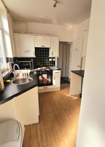 a kitchen with white cabinets and a wooden floor at Wolves Living in Bushbury