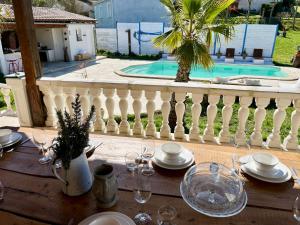 einen Tisch mit Gläsern und Tellern auf einem Balkon mit Pool in der Unterkunft Villa les cigales - Paisible avec piscine in Mas-Saintes-Puelles