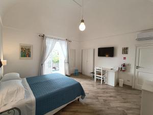 Schlafzimmer mit einem Bett, einem Schreibtisch und einem TV in der Unterkunft Regina Margherita in Positano