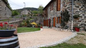 a stone house with a courtyard with flowers in front of it at Chambre d'hôte le Rosier in Araules