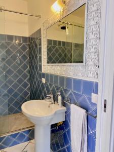 bagno piastrellato blu con lavandino e specchio di Dolcevita Villa in Vulcano a Vulcano