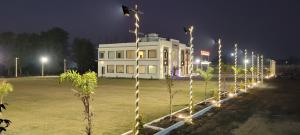 a white building with lights in a field at night at Shri Kailash Mansarovar Hotel and Marriage Garden in Sāgar