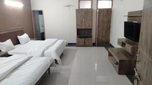 a room with three beds and a tv on a wall at HOTEL DHANUA PALACE in Chandīgarh