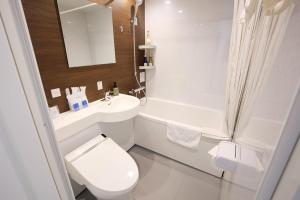 a white bathroom with a toilet and a sink at Ginza International Hotel in Tokyo