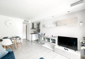 a white living room with a tv and a table at Paradise Palms I Deluxe, incl. Welcome Package in Corralejo