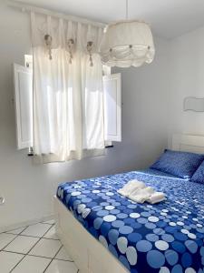 Dolcevita Villa in Vulcano في فولكانو: غرفة نوم بسرير ازرق وبيض ونافذة
