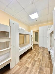 Zimmer mit weißen Etagenbetten und Holzböden in der Unterkunft Alma-Ata Hostel in Almaty