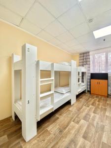 two white bunk beds in a room with wood floors at Alma-Ata Hostel in Almaty