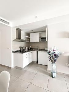 a kitchen with white cabinets and a vase of flowers at Paradise Palms I Deluxe, incl. Welcome Package in Corralejo