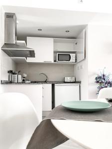 a white kitchen with a table and a microwave at Paradise Palms I Deluxe, incl. Welcome Package in Corralejo