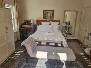 The Rose Room في هيلتون: غرفة نوم بسرير كبير عليها مقعد