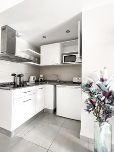 a white kitchen with white cabinets and a vase with flowers at Paradise Palms I Deluxe, incl. Welcome Package in Corralejo