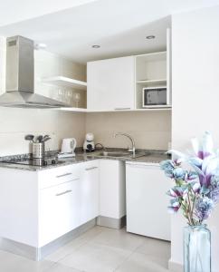 a white kitchen with white cabinets and a vase with flowers at Paradise Palms I Deluxe, incl. Welcome Package in Corralejo